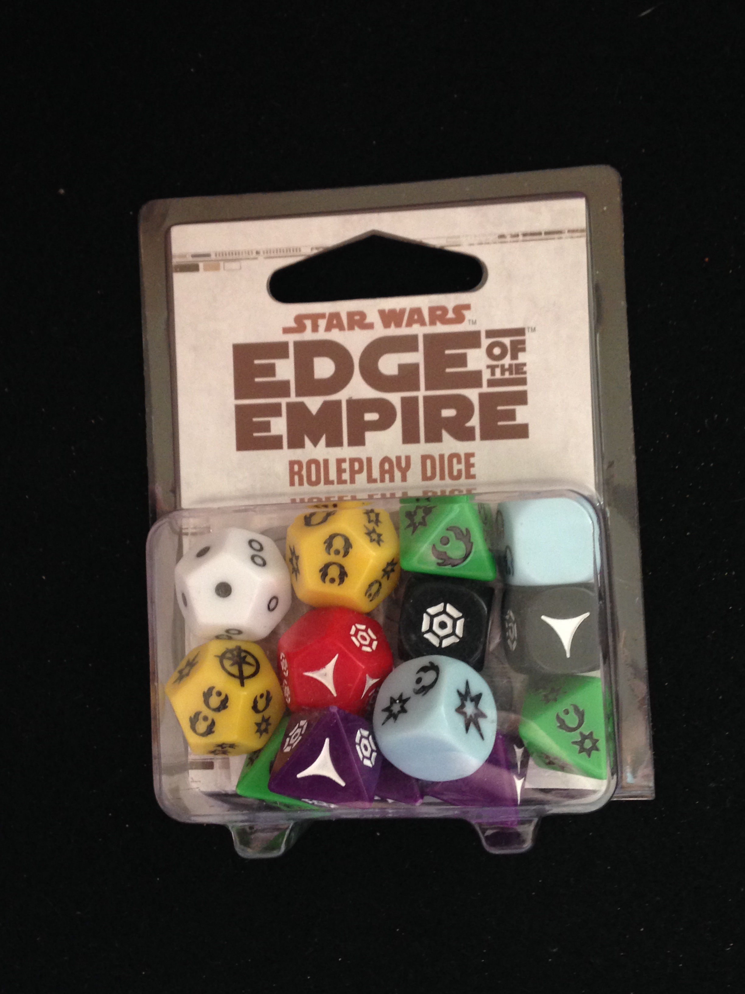 Package of multicolored symbol-marked dice labeled Star Wars: Edge of the Empire Roleplay Dice, on black fabric